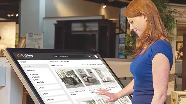 Woman using an Ashley Furniture kiosk and links to project.